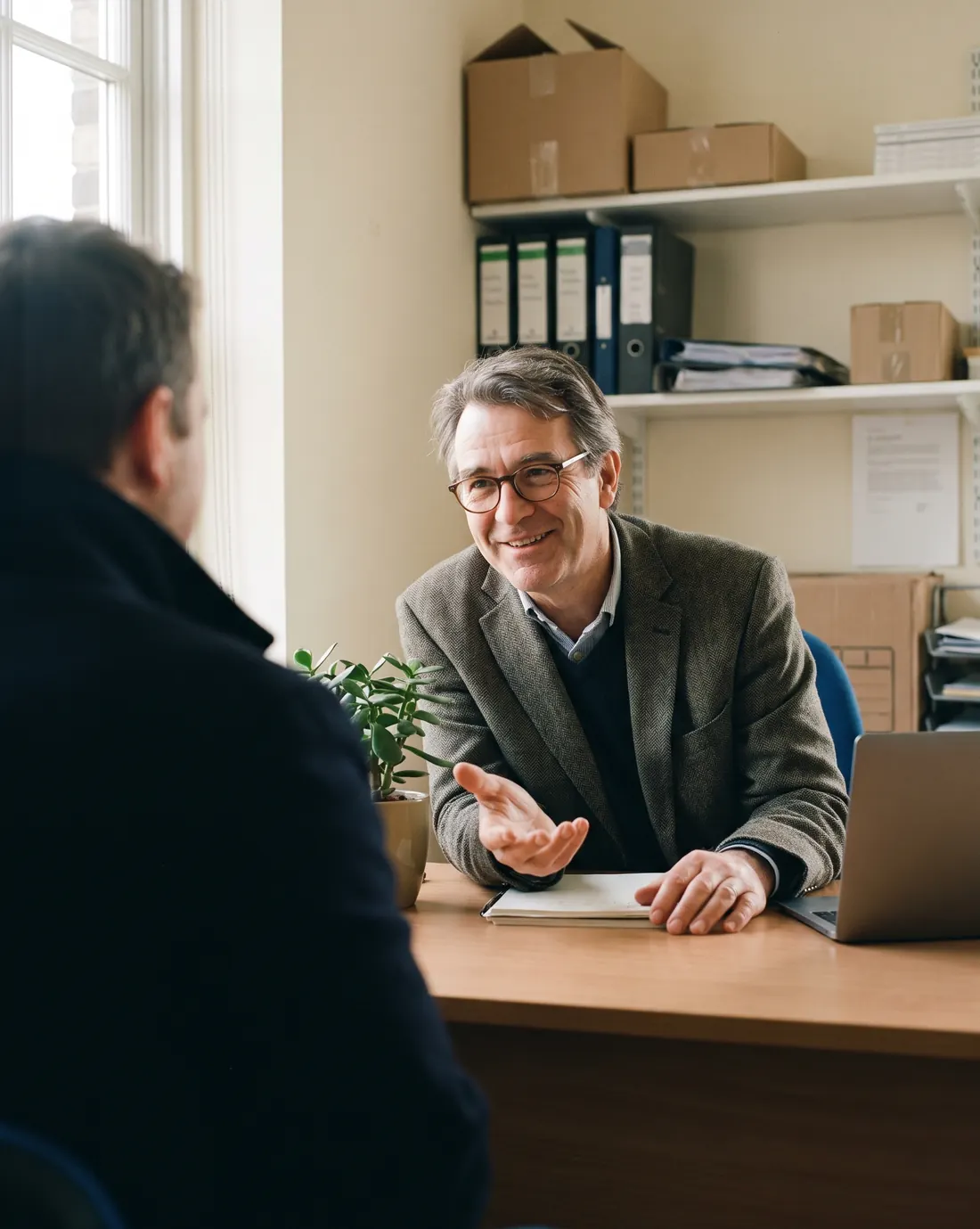 An executive assistant greeting a visitor at a front desk